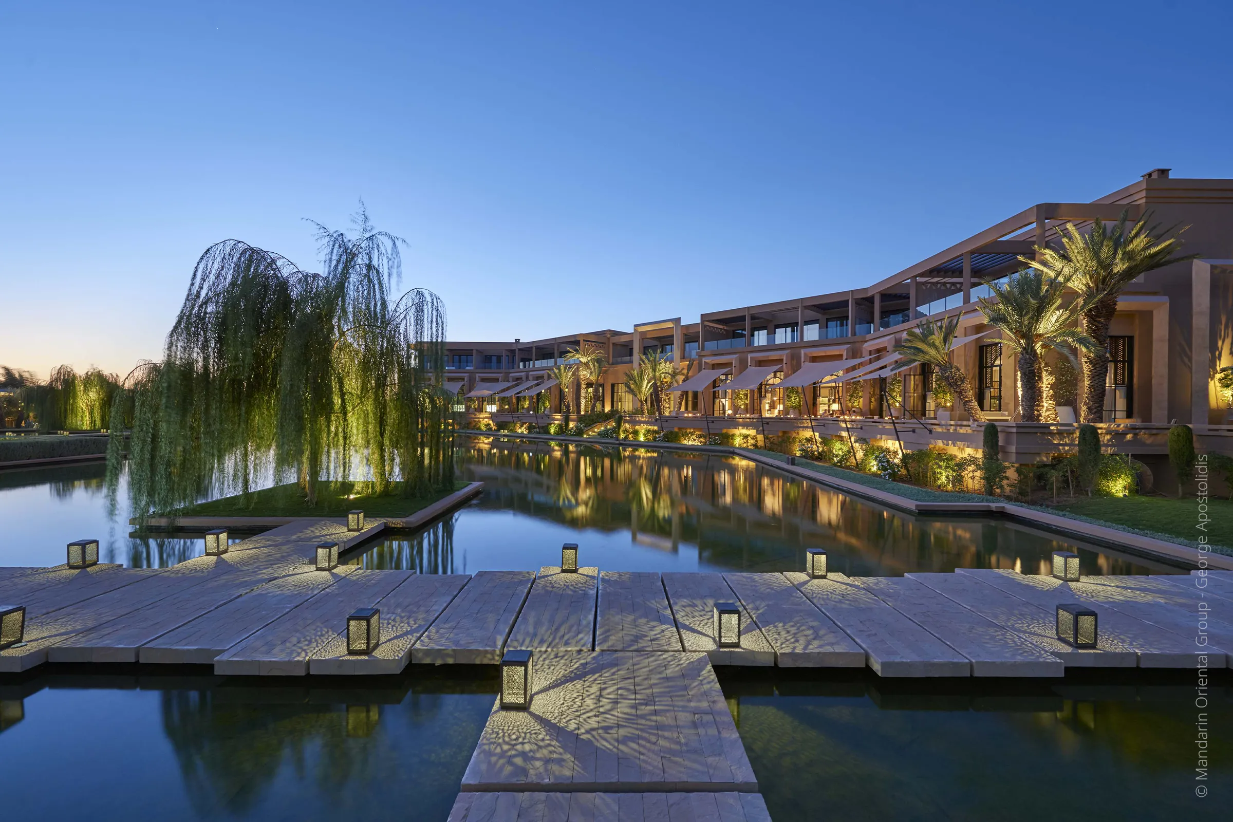 Vue exterieure nocturne du Mandarin Oriental Marrakech avec bassins et jardins illumines.