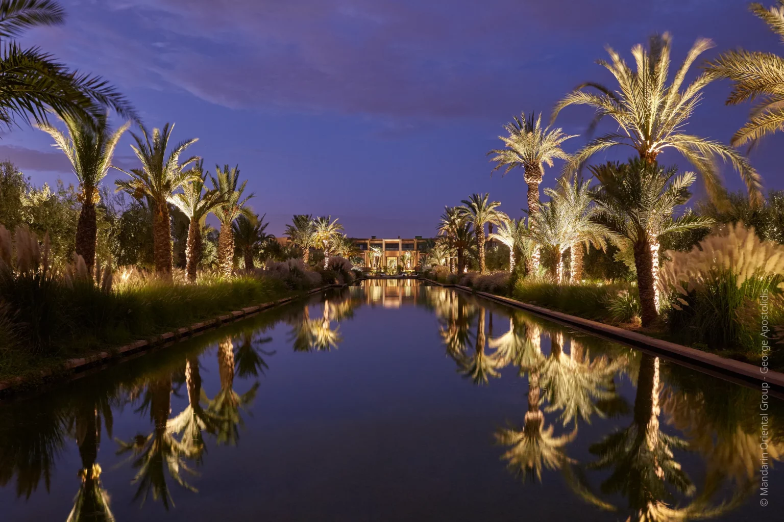 Vue extérieure du Mandarin Oriental Marrakech, avec jardins paysagers, bassin et éclairage architectural de nuit