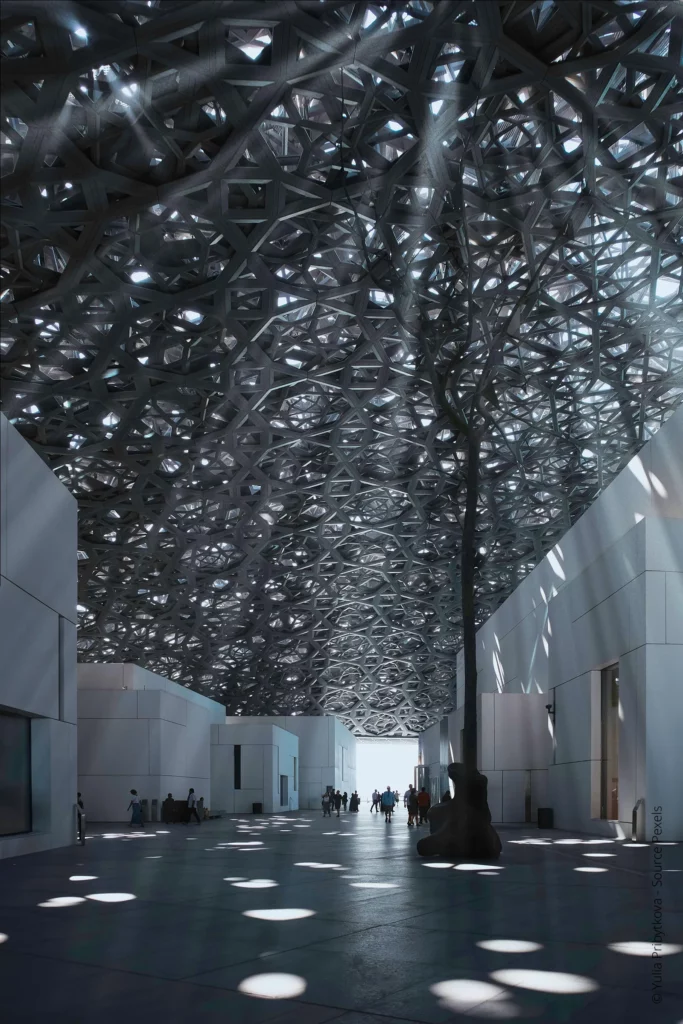 Cour intérieure du Louvre Abu Dhabi avec coupole ajourée laissant passer des rayons lumineux. Projet lumière conçu par 8’18’’ avec la participation de David Roger pendant 7 ans, des études à la phase chantier.